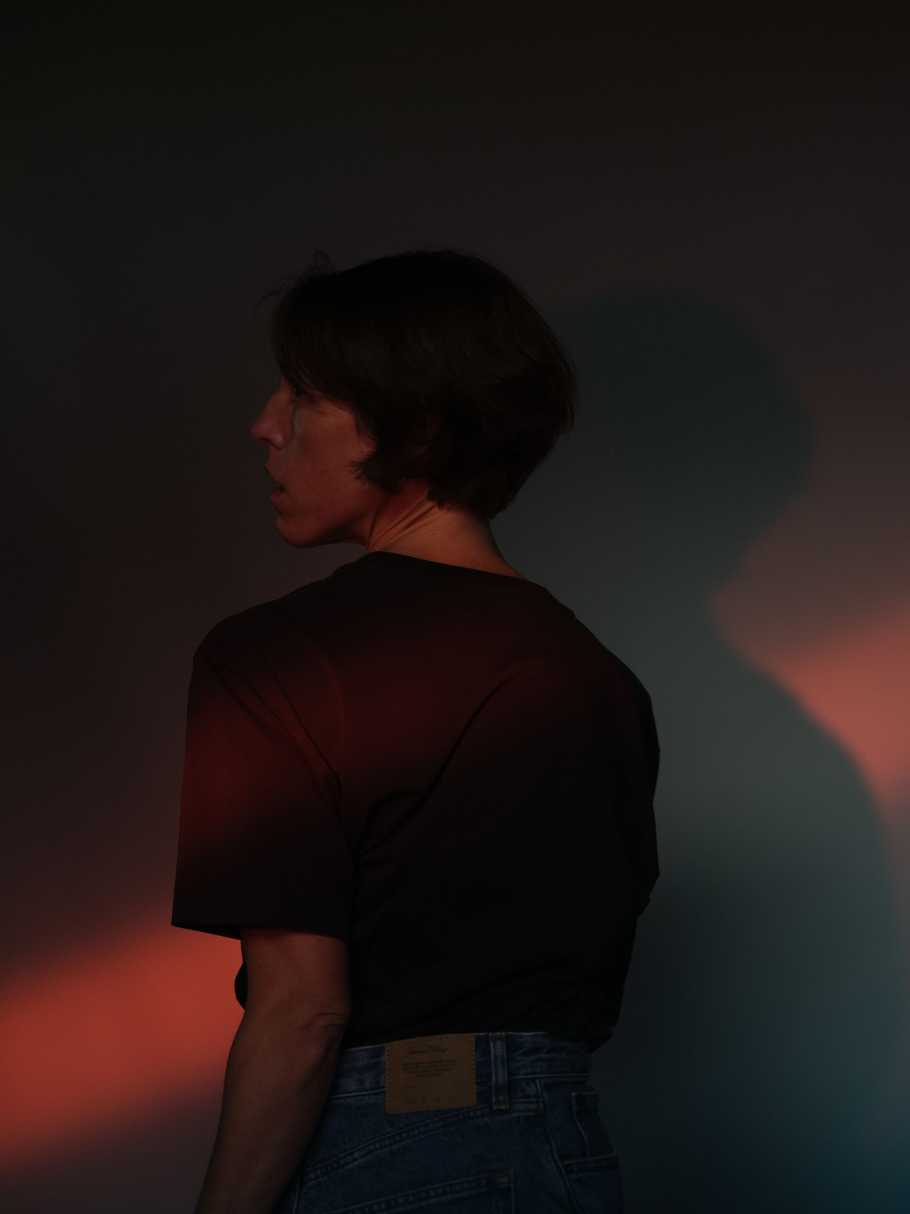 Laia Cabrera, in profile, against a dark wall lit in red and blue